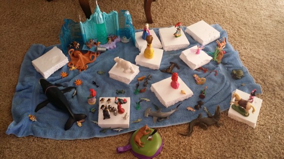 Imaginary play with dolls and figurines. Those are styrofoam "ice burgs" on a blue towel "ocean."